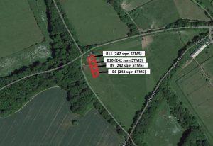 Property for sale by Auction An aerial view depicts four plots labeled B8, B9, B10, and Plot B11, each measuring 242 square meters. They are nestled in a wooded area alongside Crampshaw Lane with the postcode KT18 6BX, adjacent to a winding road and green fields. Presented by World of Auctions