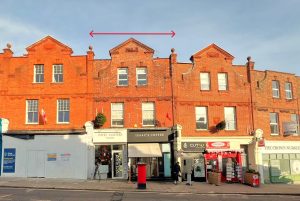 A row of red-brick buildings at 120 St. Margaret's Road, TW1 2AA, featuring store signs like "David Masters Salon," "Isaac's Coffee," "Cut-U," and "The Crown Nutrition." Available for sale by auction with World of Auctions, London, this mixed commercial and residential investment boasts decorative brickwork and dormer windows. A few people are seen walking