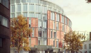 The future Harrods conneted hotel Modern building with a curved facade, featuring red brickwork and vertical white elements, surrounded by autumnal trees