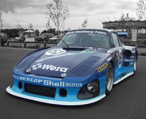 Property for sale by Auction A blue and light blue race car with various sponsor logos including Dunlop, Shell, and Valvoline, is parked in an outdoor lot. The number 61 is prominently displayed on the hood and doors. The background is muted in color, emphasizing the vibrant car. Presented by World of Auctions