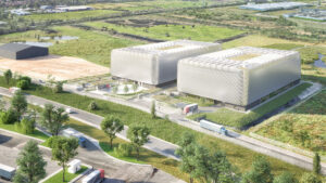 Property for sale by Auction Aerial view of a modern data center facility featuring two large white rectangular buildings, surrounded by a green landscape with trees and grassy fields. Several trucks are seen on a road in the foreground, and additional buildings are visible in the distance. Presented by World of Auctions