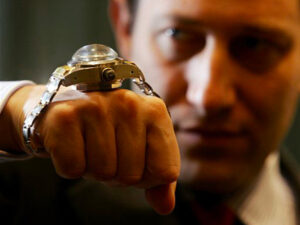 Property for sale by Auction A person in a suit showcases a luxury watch with a large, domed crystal and intricate design, capturing the essence of sophistication. The focus is solely on the timepiece, symbolizing the excellence highlighted in the Luxury Watch Market Update for Q3 2024. Presented by World of Auctions