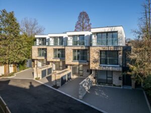 Property for sale by Auction A modern, multi-story apartment complex with a brick and glass exterior is now available as your new home for sale in Wimbledon. The building boasts large windows and balconies, surrounded by trees and a paved driveway under a clear blue sky. Presented by World of Auctions