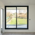 Property for sale by Auction A bright room in this Wimbledon new home for sale features large sliding glass doors opening to a balcony with views of a grassy lawn and trees. The minimalist interior, with light-colored walls and carpeting, creates an airy atmosphere. Presented by World of Auctions