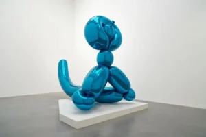 Property for sale by Auction A shiny, metallic blue balloon-like sculpture shaped like a simplified animal figure is displayed on a white platform in a minimal gallery space with grey flooring and white walls. Presented by World of Auctions