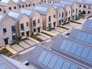 Property for sale by Auction Aerial view of a modern housing development featuring rows of brick houses with solar panels on the roofs. The homes boast driveways and landscaped front yards, showcasing sustainable energy—part of the powerhouse driving the UK's 2% GDP growth in August 2024. Presented by World of Auctions