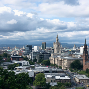 Property for sale by Auction The cityscape view blends historical and modern architecture, a scene straight from the Glasgow Property Investment Guide. Ornate spires rise above, juxtaposed against partly cloudy skies, with lush greenery softly framing this vibrant urban tapestry. Presented by World of Auctions