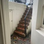Property for sale by Auction A narrow, outdoor brick staircase with a black metal railing ascends from the lower level, embraced by white walls. Fallen leaves add charm to the steps of this investment apartment in Brighton BN3, set against a backdrop of buildings and up for sale by auction. Presented by World of Auctions